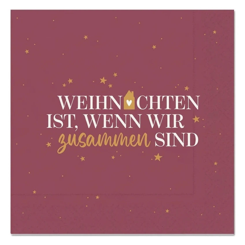 Bordeauxrote Serviette mit goldfarbenen Sternen und dem Schriftzug „Weihnachten ist, wenn wir zusammen sind“ in Weiß und Gold