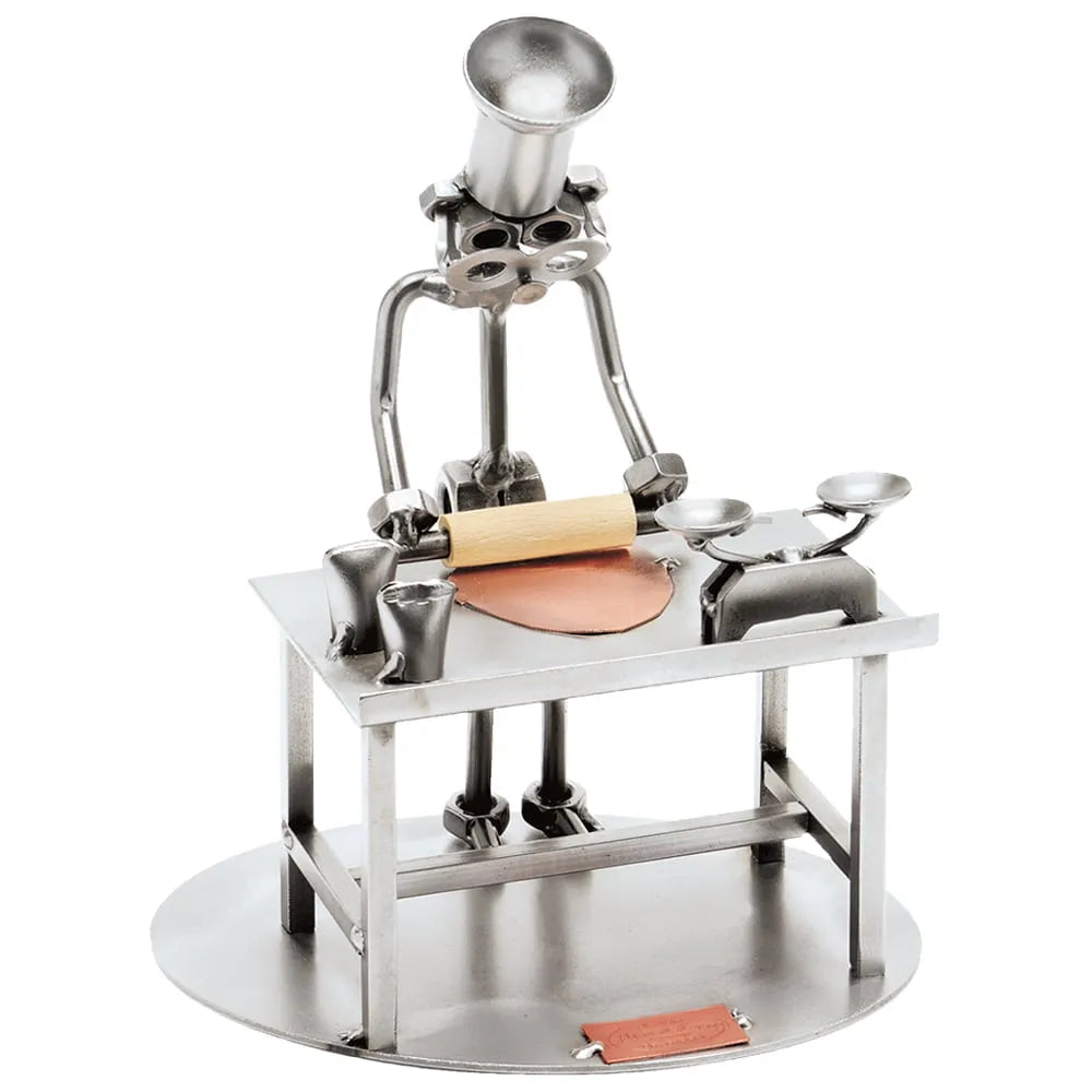 Schraubenfigur als Konditor mit hoher Kochmütze und Nudelholz an einem Arbeitstisch mit Teig und Waage.
