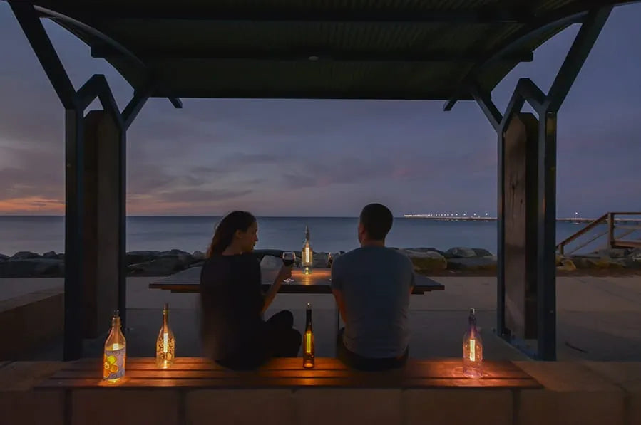 Bottlelight dimmbare LED-Flaschenlampe – 15/40 lm warmweiß/weiß – Moodbild mit einem Paar auf einer Strandterrasse am Meer in Abendstimmung