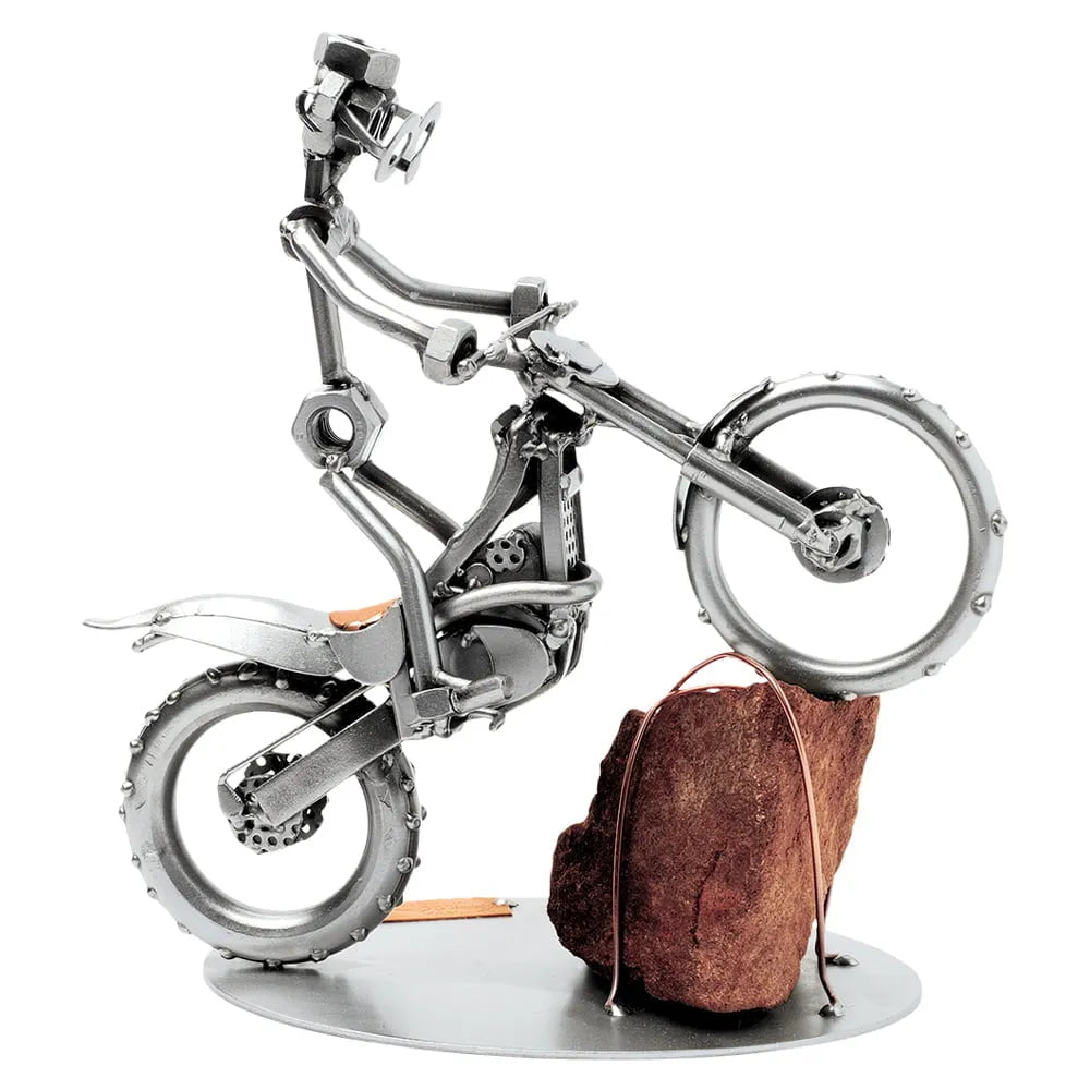 Schraubenfigur eines Trialfahrers auf einem Crossmotorrad mit dem Vorderrad auf einem rötlichen Felsen
