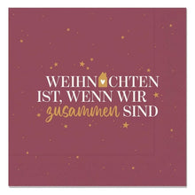 Bordeauxrote Serviette mit goldfarbenen Sternen und dem Schriftzug „Weihnachten ist, wenn wir zusammen sind“ in Weiß und Gold