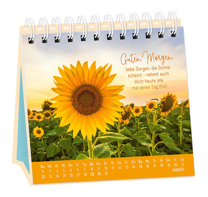 Tischkalender - "Extraportion Glück" - 2027 - Monat August - Spruch: "Guten Morgen, liebe Sorgen, die Sonne scheint - nehmt euch doch heute alle mal einen Tag frei!" Design: Ein Feld voller Sonnenblumen.