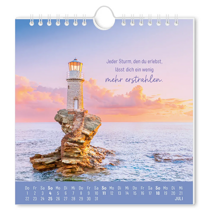 Postkartenkalender - "Strandgut" - 2027 - Monat Juli - Ein Leuchtturm  auf einem Felsvorsprung mitten im Meer mit dem Spruch "Jeder Sturm, den du erlebst, lässt dich ein wenig mehr erstrahlen." 