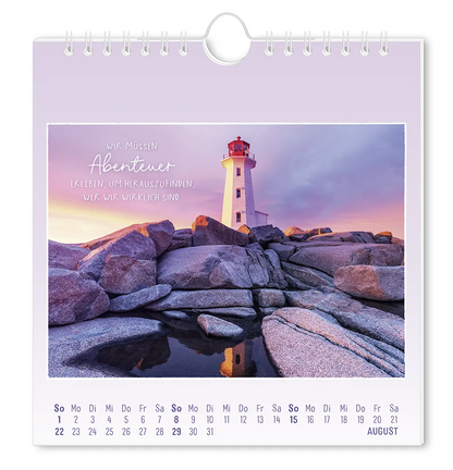 Postkartenkalender - 2027 - "Traumtage" - Monat August - Steinige Landschaft mit Blick auf einen Leuchtturm im Hintergrund mit dem  Spruch "Wir müssen Abenteuer erleben, um Herauszufinden, wer wir wirklich sind."