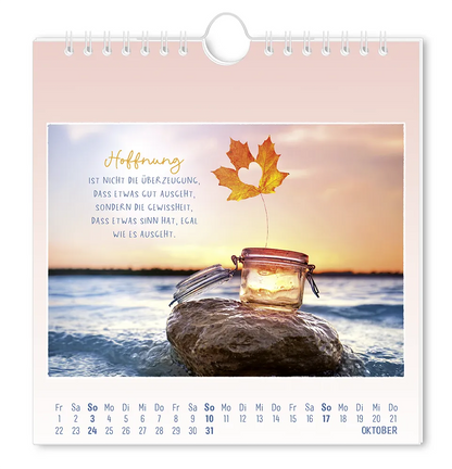 Postkartenkalender - 2027 - "Traumtage" - Monat Oktober - Ein Blatt mit Herzausschnitt, dass aus einem Glas herausragt, welches auf einem Stein im Wasser liegt, mit dem Spruch "Hoffnung  ist nicht die Überzeugung, dass etwas gut ausgeht, sondern die Gewissheit, dass etwas Sinn hat, egal wie es Aussieht."