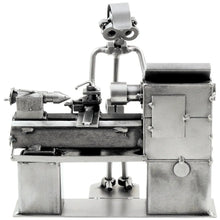 Silberfarbene Schraubenfigur eines Zerspanungsmechanikers bei der Arbeit an einer detailreichen Drehmaschine.⠋