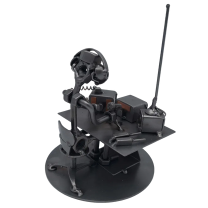 Schraubenfigur eines Funkers mit Kopfhörern am Funkgerät, schräg von hinten mit Blick auf Tisch, Stuhl und hohe Antenne