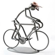 Metallmännchen als Rennradfahrer mit Brille und kupferfarbener Kappe, nach vorn gebeugt auf einem Rennrad