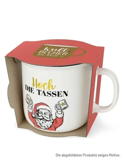 Weißer Kultbecher mit Schriftzug „Hoch die Tassen“ und Weihnachtsmann mit zwei erhobenen Bechern in offener roter Geschenkverpackung