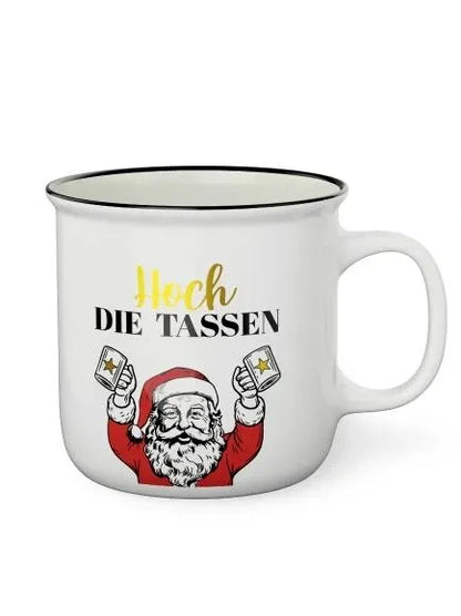 Weißer Kultbecher mit schwarzem Rand, Schriftzug „Hoch die Tassen“ und Weihnachtsmann mit zwei erhobenen Bechern