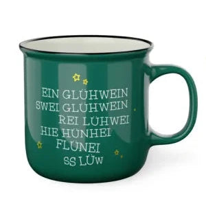 Grüner Kultbecher mit schwarzem Rand, kleinen goldfarbenen Sternen und humorvollem, zunehmend verdrehtem Glühwein-Schriftzug