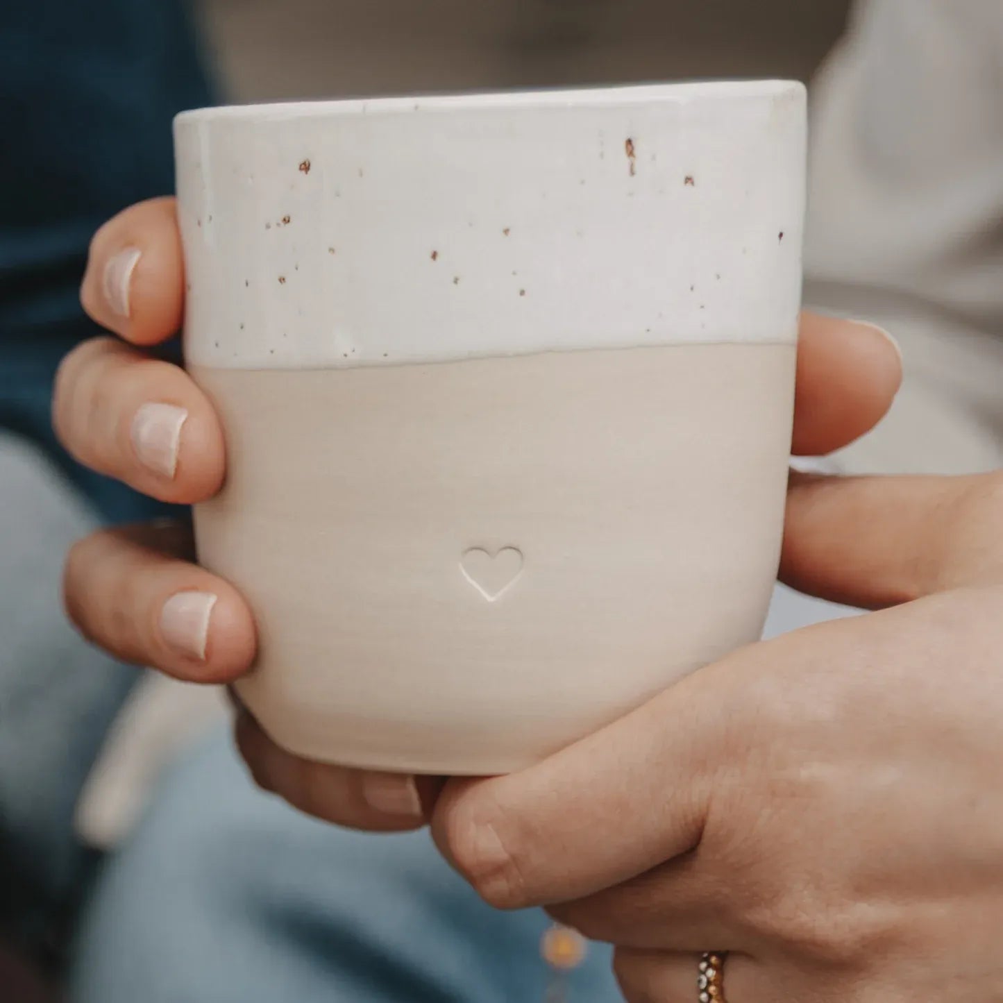 Handgefertigter Becher "Herz" aus Steingut in den Händen