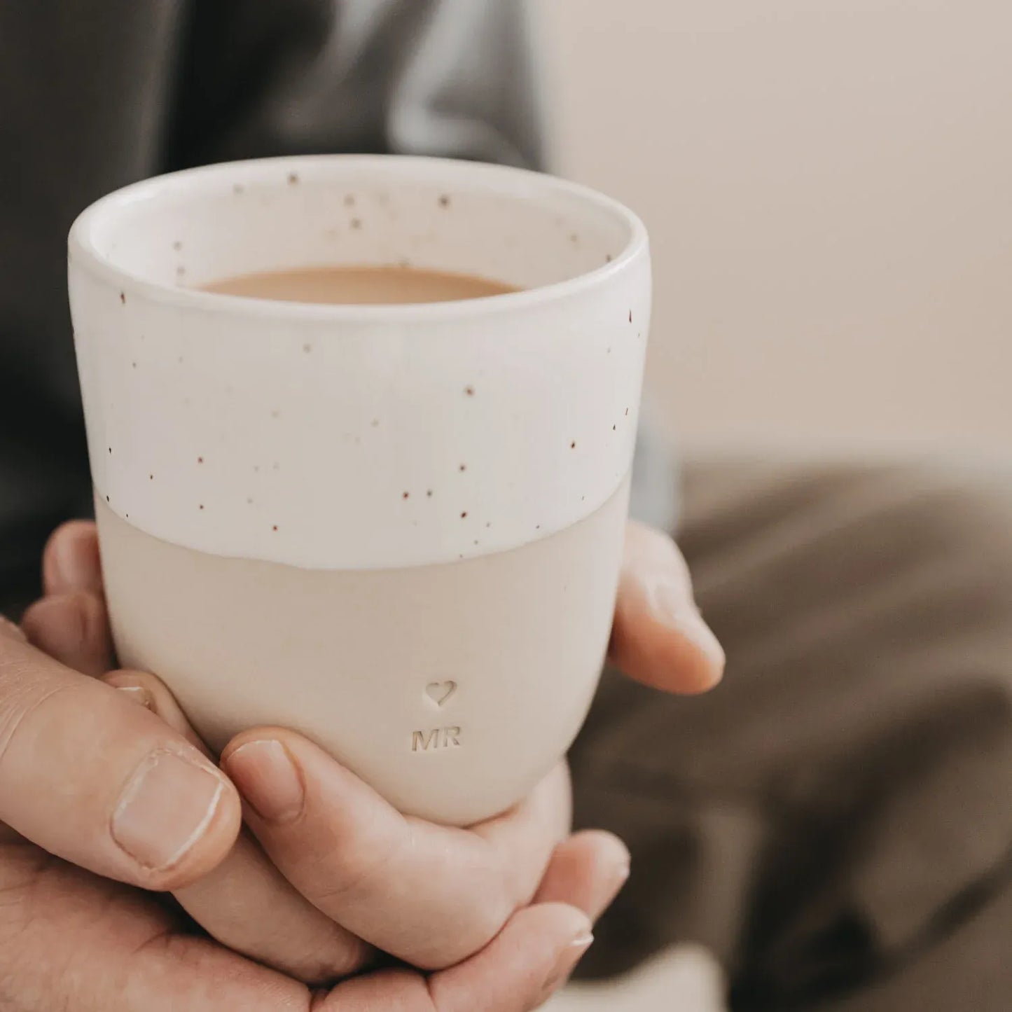 Handgefertigter Becher "Mr" aus Steingut in den Händen
