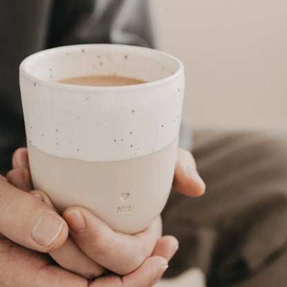 Handgefertigter Becher "Mr" aus Steingut in den Händen