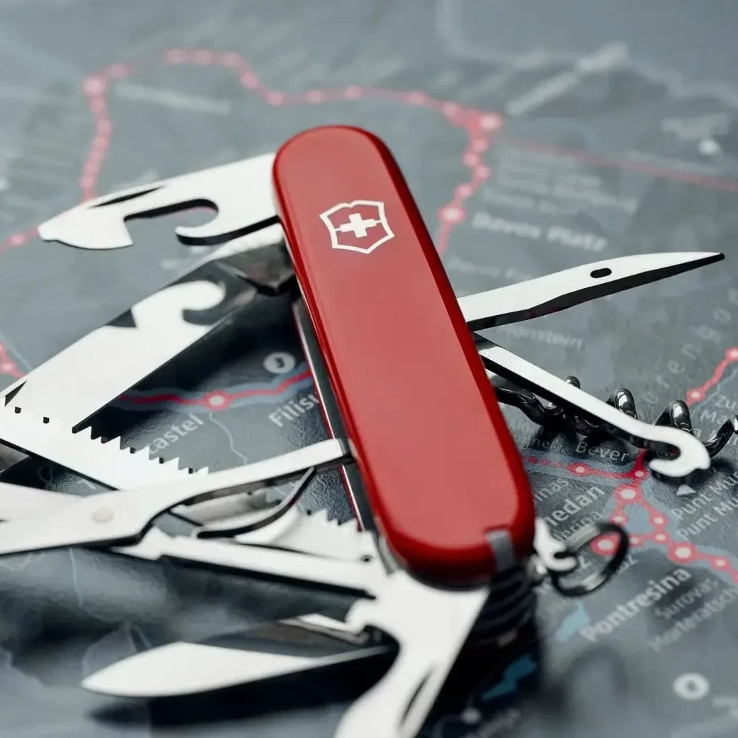 Rotes Victorinox Taschenmesser mit ausgeklappten Werkzeugen auf einer Landkarte als hochwertiges Geburtstagsgeschenk