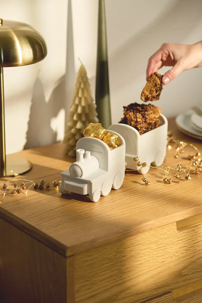 Räder Weihnachtszug-Schalen-Set aus weißem Porzellan, gefüllt mit Süßigkeiten und Gebäck auf einer weihnachtlich dekorierten Holzkommode
